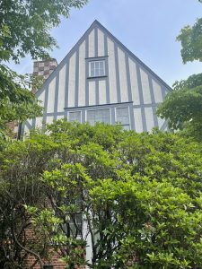 Tudor style house with black and white exterior and lush green bushes in front.