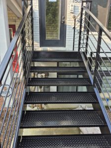 Outdoor metal staircase with safety railings and textured steps for slip resistance.