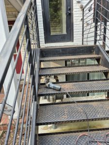 Industrial metal staircase with safety railings and a door in the background.
