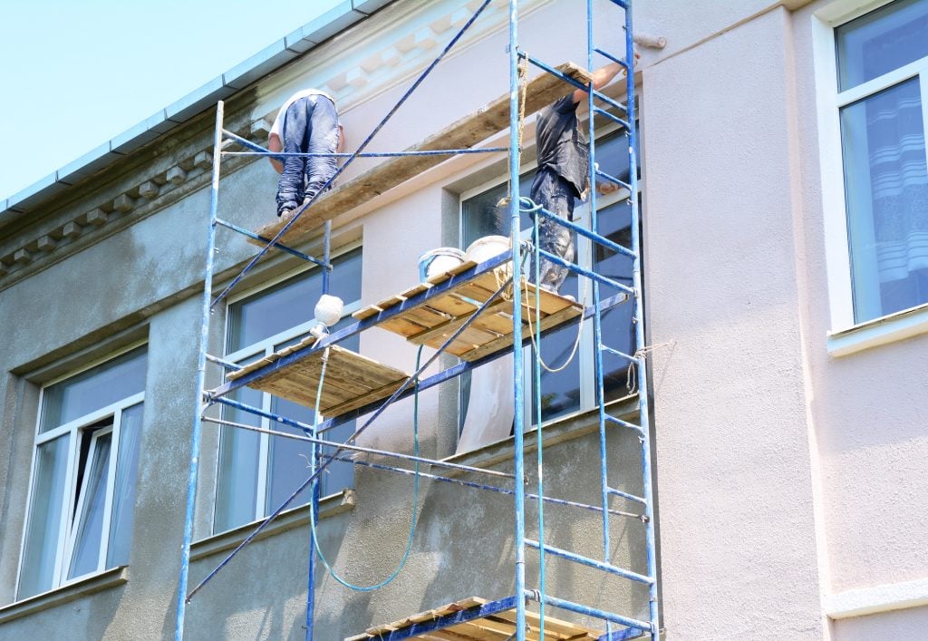 Builder contractors painting walls outside house facade